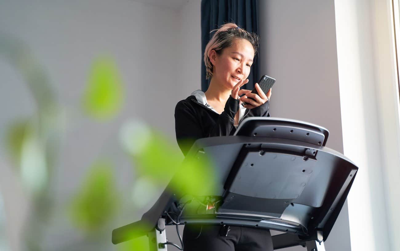 Woman syncing her phone to her treadmill.