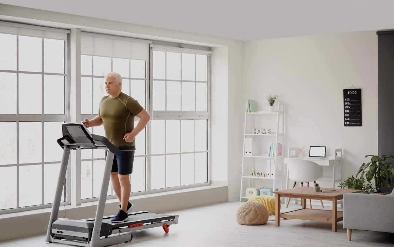Older man running on a treadmill in his living room.