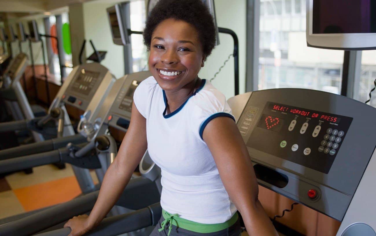 Woman on a treadmill smiling at the camera.