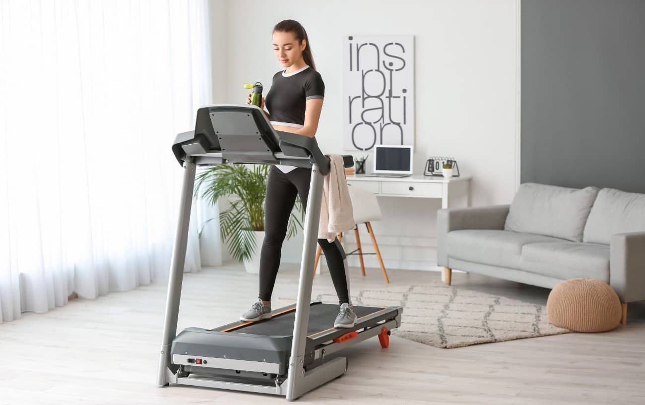 Girl walking on a treadmill in her living room.