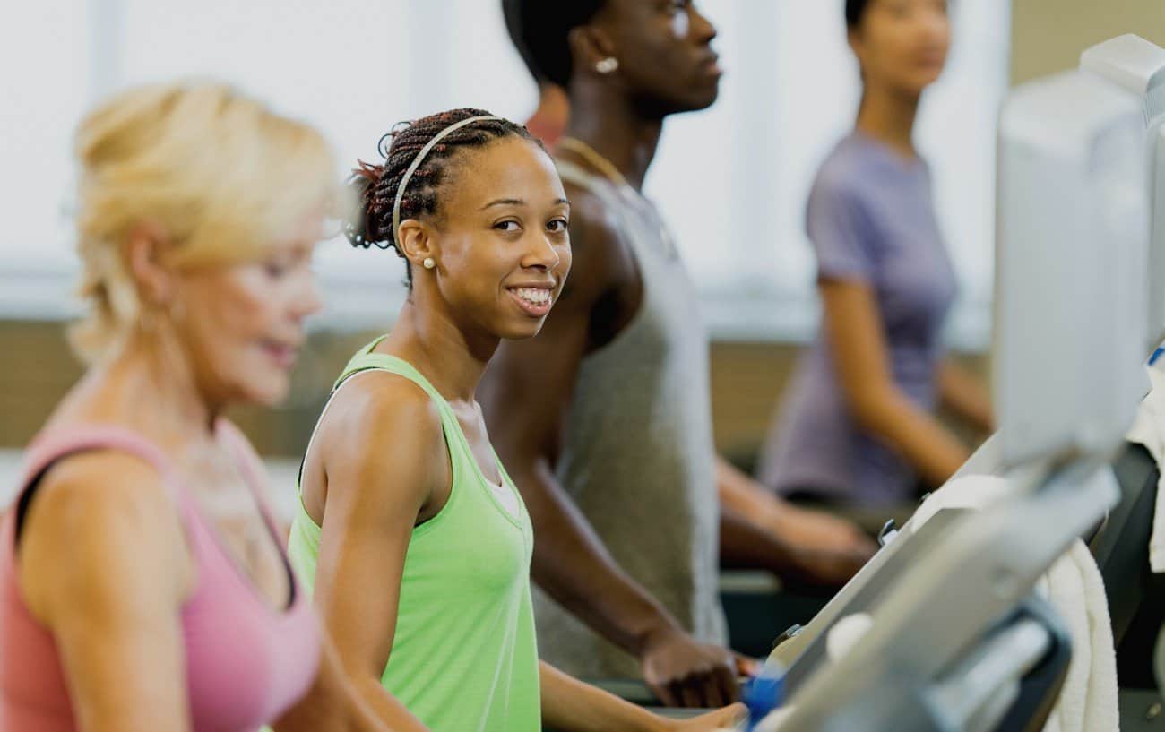 Woman standing on a treadmill and smiling at the camera.