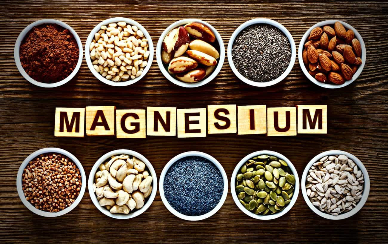 A sign that says "magnesium", surrounded by cups of different nuts and seeds.