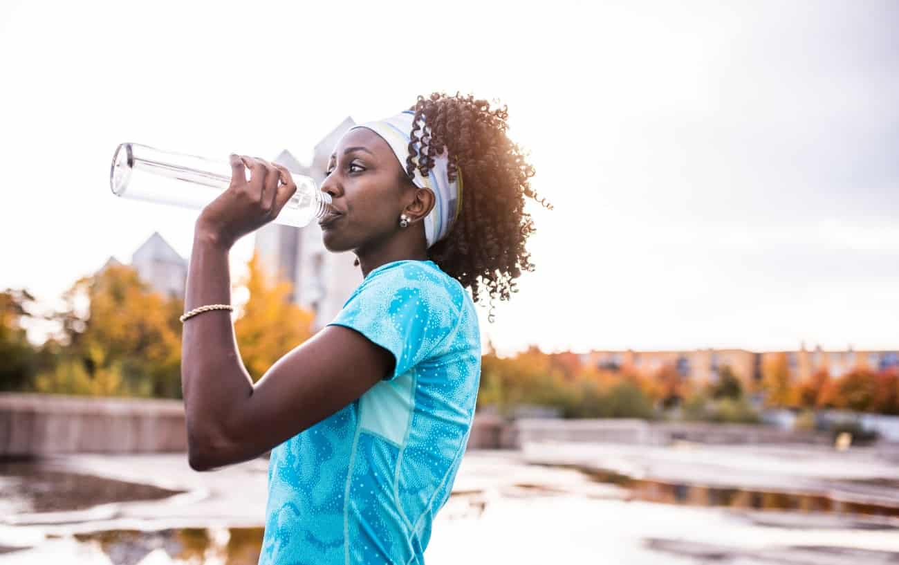 Female runner drinking water.