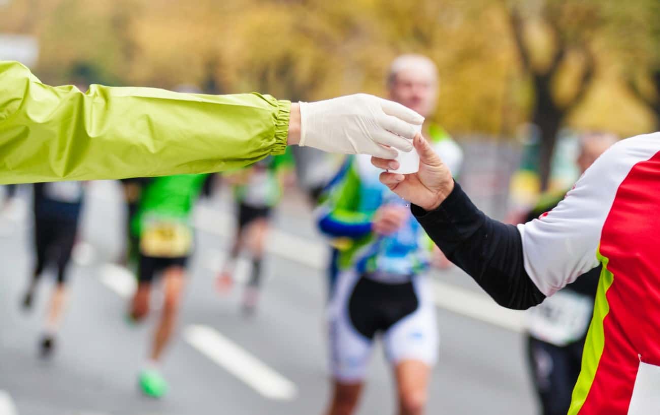 Race helper handing a runner some water.