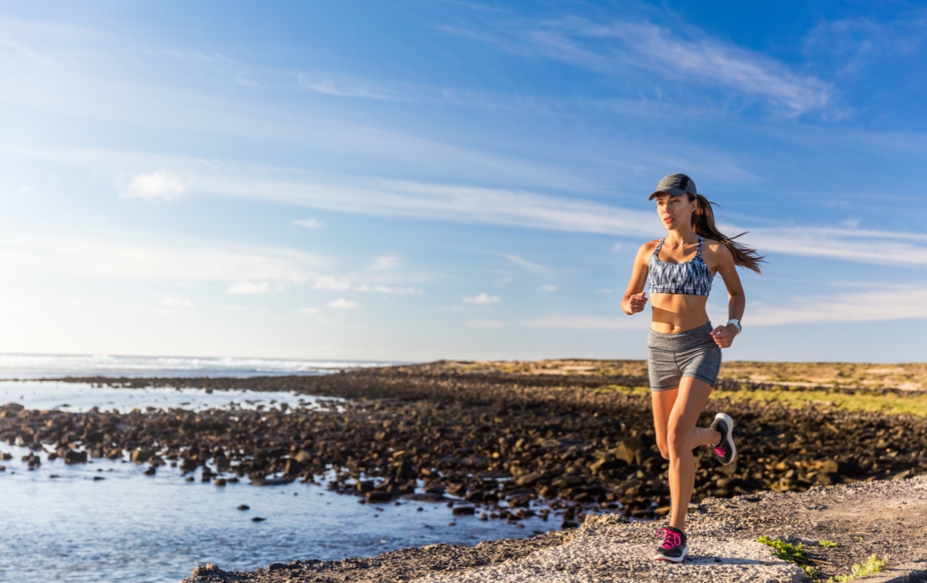 Woman with cap running next to sea