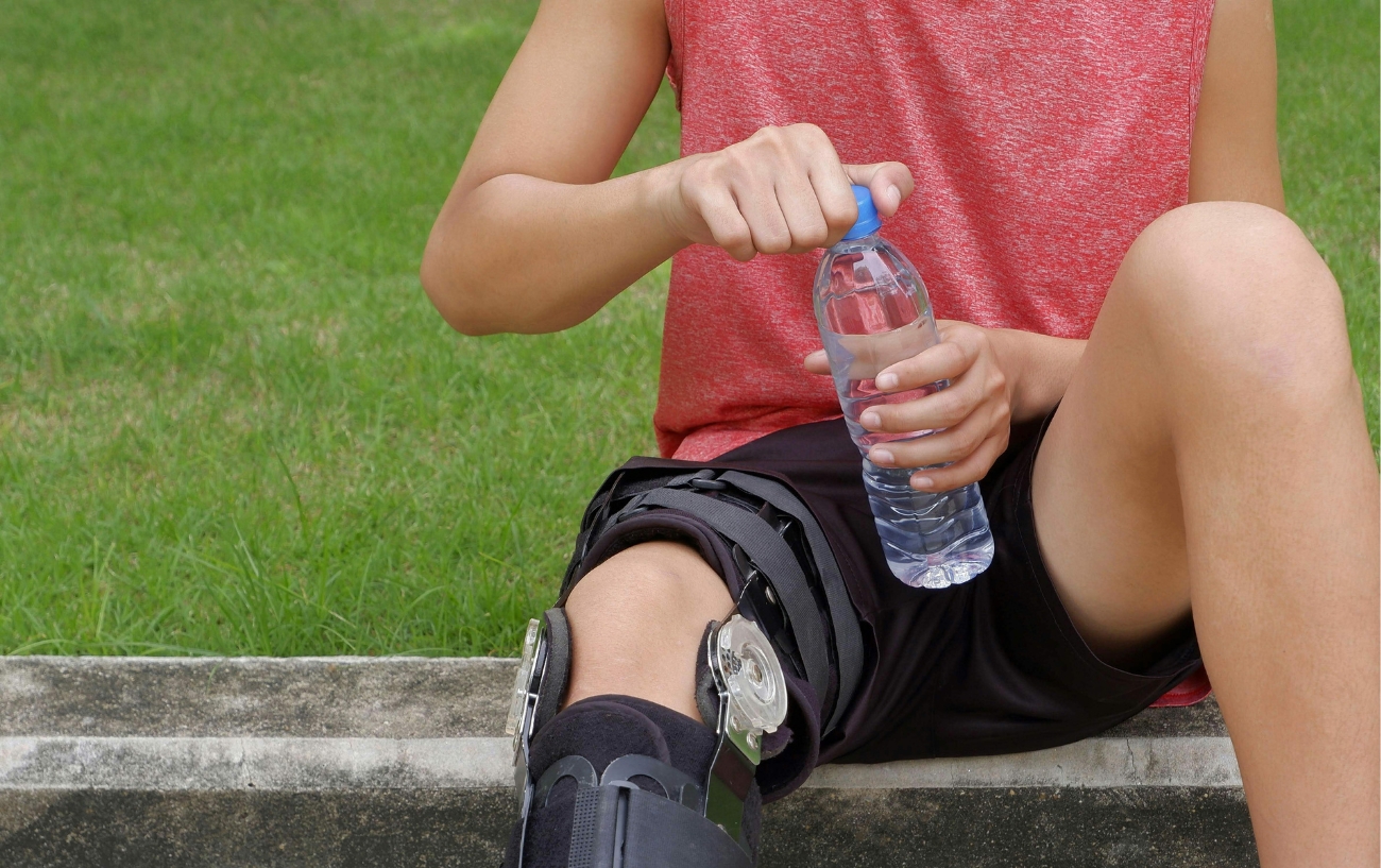 person drinking water with knee brace