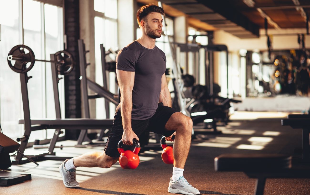 man lifting kettlebells in lunge pose